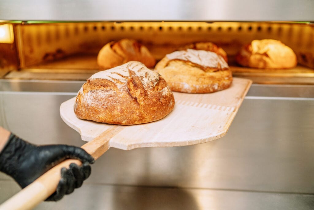 Baker putting bread in the bakery oven